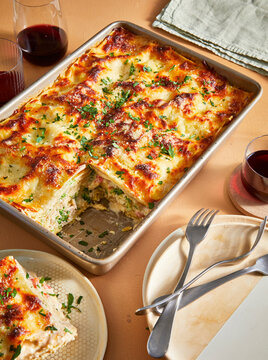 white lasagna with slice out on table with wine