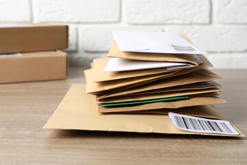 Different paper envelopes and parcels on wooden table, closeup. Post office