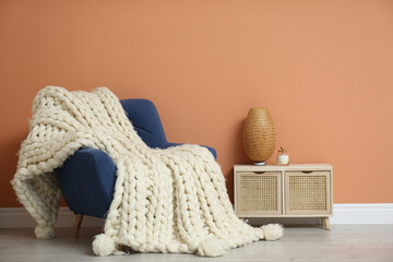 Fototapeta premium Knitted merino wool plaid on armchair in room