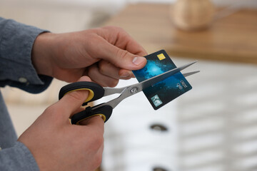 Man cutting his credit card indoors, closeup