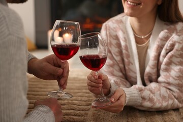 Couple with glasses of wine on floor at home, closeup