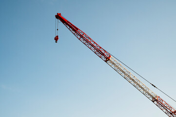 Red and white construction crane against clear blue sky