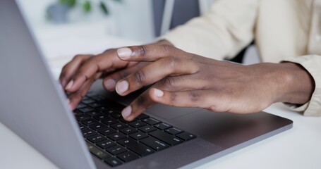 a dark-skinned guy in a light shirt is slowly typing on a laptop standing on a white table hands...