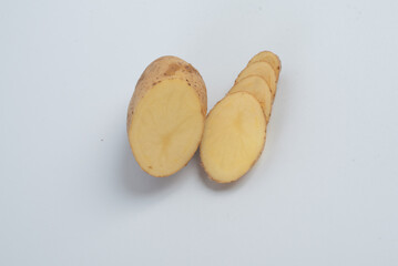 This image shows a fresh potato that has been partially sliced into thin, even rounds. The potato’s skin is light brown and slightly rough, while the inside is a pale yellow, indicating its freshness 