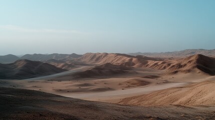 Obraz premium A vast desert with gentle sand dunes under a clear blue sky, evoking a timeless, serene quietude and raw natural beauty.