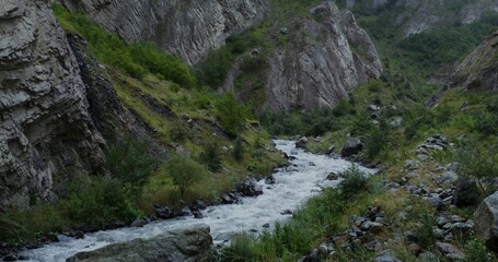 Mountain river, seething with a strong stream among the rocks. The tops of the mountains are covered with thick clouds. Daylight video