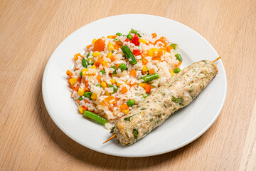 A vibrant plate showcases vegetarian skewers alongside a hearty mix of colorful rice and veggies