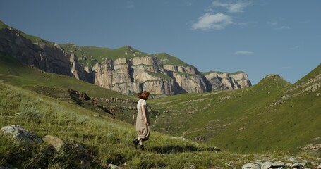 Russia, Caucasus. A young beautiful woman of European appearance descends the hillside and stops on...