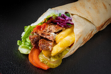 Wrapped delight has tender meat, crisp lettuce, veggies, and zesty sauces for a wholesome bite