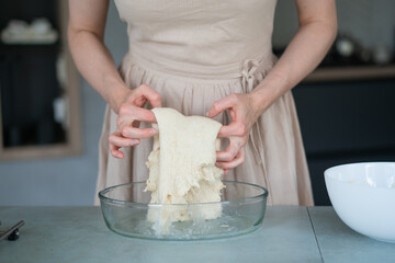 Girl in the kitchen in a beige dress preparing dough