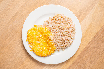 Savor a delightful combination of seasoned rice and a golden egg omelet on a simple white plate