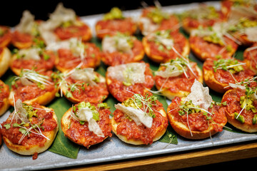 A tray of appetizers with a variety of toppings, including meat, cheese, and vegetables