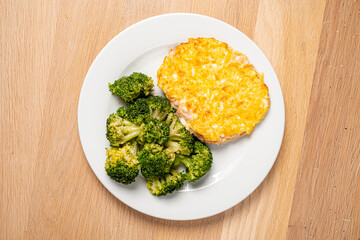 A delightful plate features a cheesy baked dish alongside fresh green broccoli on a wooden surface