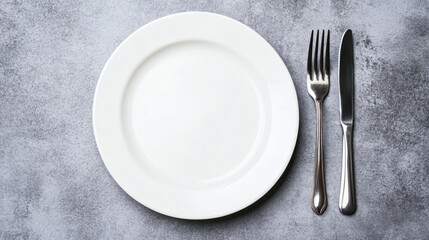 Minimalist table setting with empty plate, fork, and knife on gray surface for design application in dining themes