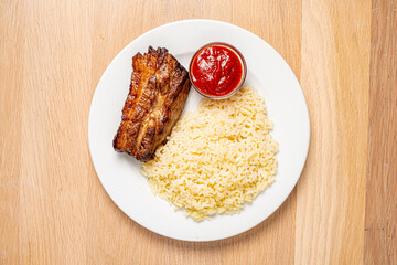 Delicious grilled pork with a side of soft rice and vibrant dipping sauce awaits your taste buds