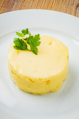 A savory potato dish rests elegantly on a white plate, topped with fresh parsley sprigs