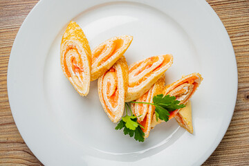 Fresh rolls filled with creamy cheese and smoked salmon, skillfully arranged on a plate with herbs