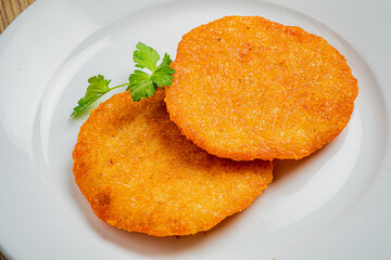 Two golden snacks on a plate, garnished with fresh herbs, look inviting