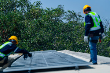 Fototapeta premium Two engineers install solar panels on a rooftop, wearing safety gear and helmets. The scene showcases renewable energy, green technology, and sustainable solutions under a clear blue sky.