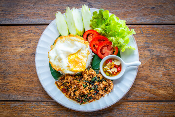 Spicy fried pork with basil leaves, traditional Thai food served with jasmine rice and fried egg table top view.