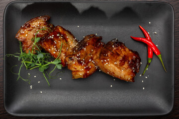 Stewed meat with sesame on a black plate, Japanese cuisine