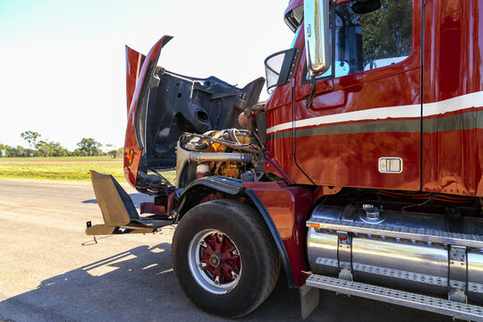 A red or maroon semi-trailer broken down with bonnet up.