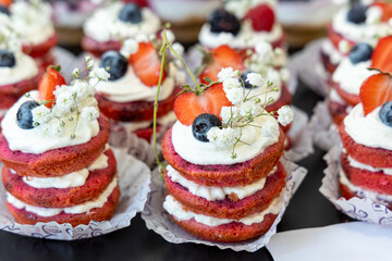 Delicious mini layer cakes with pink sponge, whipped cream, fresh strawberries, blueberries, and delicate white flowers. Perfect for weddings, birthdays, and elegant dessert tables.