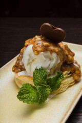 Dessert with puff pastry and ice cream drizzled with caramel on a plate