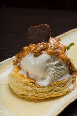 Dessert with puff pastry and ice cream drizzled with caramel on a plate