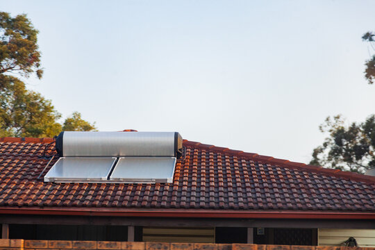 Solar panel and hot water heater on tilled roof of home