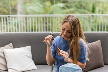 Woman applying essential oil from a dropper bottle at home