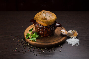 A pot with baked meat and a bread lid on a wooden stand