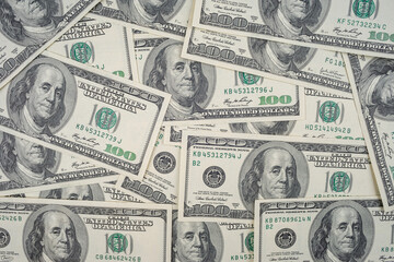 Scattered US hundred dollar bills with Benjamin Franklin portrait. Flat lay composition of American banknotes for finance and investment concept.