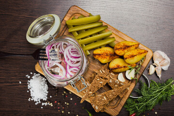 Herring with onions in a glass jar with potatoes and pickled cucumber