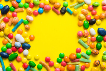 Obraz premium Mixed collection of colorful candy, on colored background. Flat lay, top view. frame of colorful chocolate coated candy