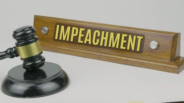 "Impeachment" text on a nameplate beside a gavel, symbolizing the legal process by which a government official, typically a president, is formally charged with misconduct or crimes