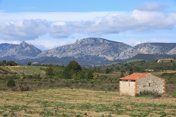 Old stone building in field on farmland in valley against backdrop of Corbi&egrave;res mountain range, near Tautavel in Pyr&eacute;n&eacute;es-Orientales department, southern France