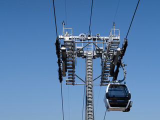 Close-up view of the support tower and the cable car in the mountains against the sky