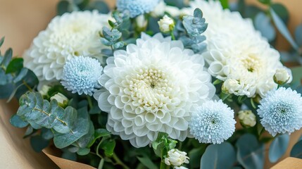 Delicate bouquet of powder blue and white flowers in kraft paper wrap