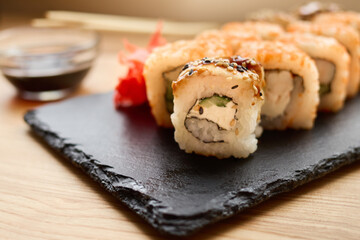 Close-up of sushi rolls displayed on a dark slate board alongside pickled ginger and soy sauce. This setting captures the essence of a cozy dining experience