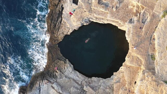  Above aerial slow motion view of a girl floating and swimming in Giola lagoon, natural pool near the sea, in Thassos island, Greece