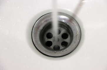 The stream of water flows into the drainhole in the porcelain sink