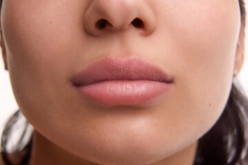 Cropped close-up image of beautiful female face, plump lips with nude lipsticks makeup isolated...