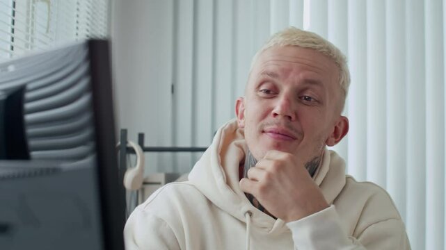 Medium close up shot of male Caucasian tester with tattoo on neck finding bug in coding script while working on computer at office desk