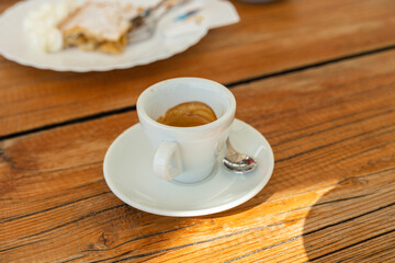 tazzina con caffè espresso, al bar, su un tavolo di legno, accompagnata con un piatto di strudel con due forchette