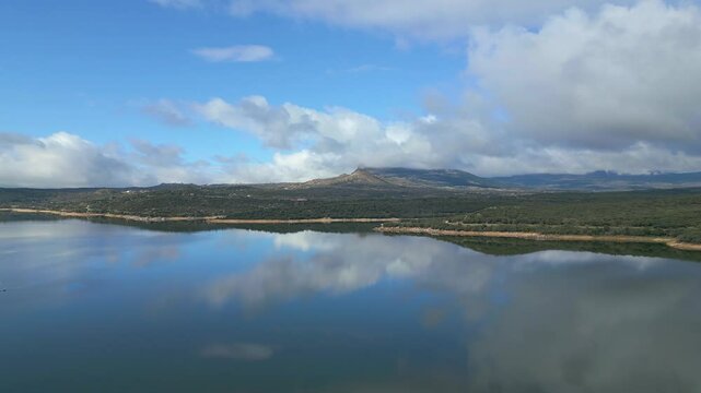 Beautiful lake of calm water and reflections of the blue sky with storm clouds, El Atazar, Madrid.