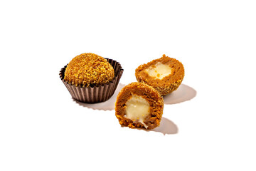 Honey ball in brown wrapper and next to it cut in half with milk filling on white background. Candy on white background.