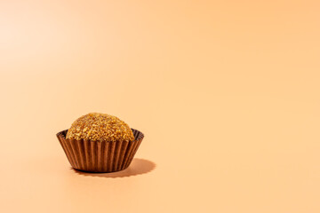 Honey ball in brown wrapper on orange background. Candy on orange background.