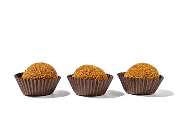 Three small brown pastries in paper cups. They are sitting on a white background. The pastries are in the middle of the image