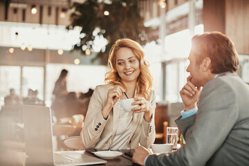 Businesswoman and colleague having coffee and conversation at modern cafe